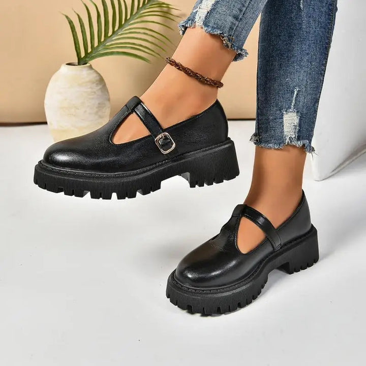Close-up: T-strap and buckle details on black platform orthopedic Mary Jane shoes for women.