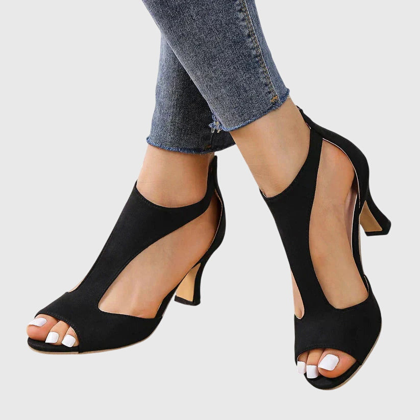 Women's black peep toe block heel sandals featuring chic cut outs, an ankle zip, and a comfortable sole.