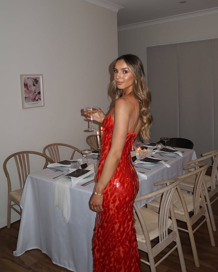 Fitted red sequin evening gown, featuring a V-neckline, backless style, and mermaid silhouette.