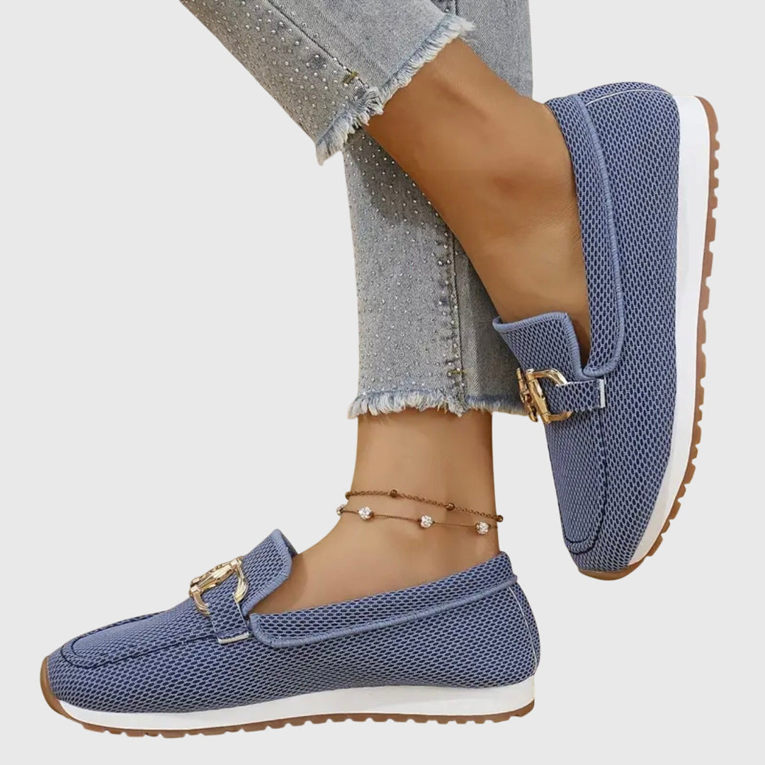Pair of dusty blue women's loafers with a sleek horsebit buckle. Comfortable, stylish, and versatile casual shoes.
