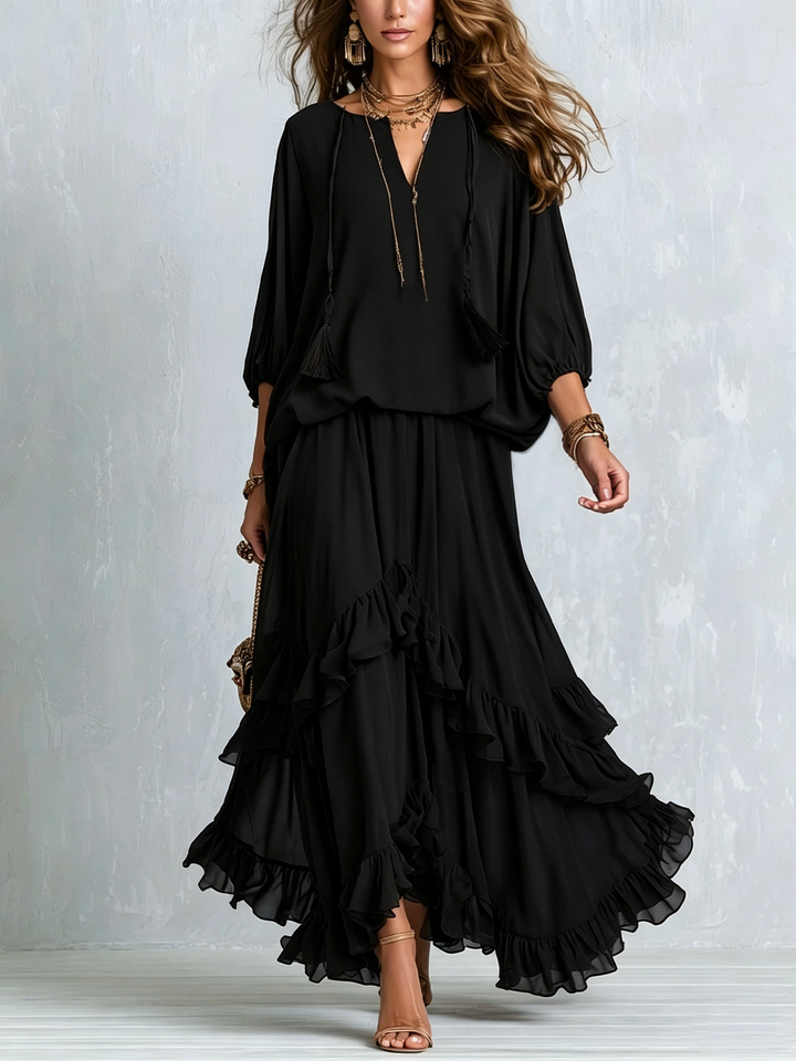 Elegant black boho maxi skirt set, two-piece with tassel V-neck top, lantern sleeves & tiered ruffles.