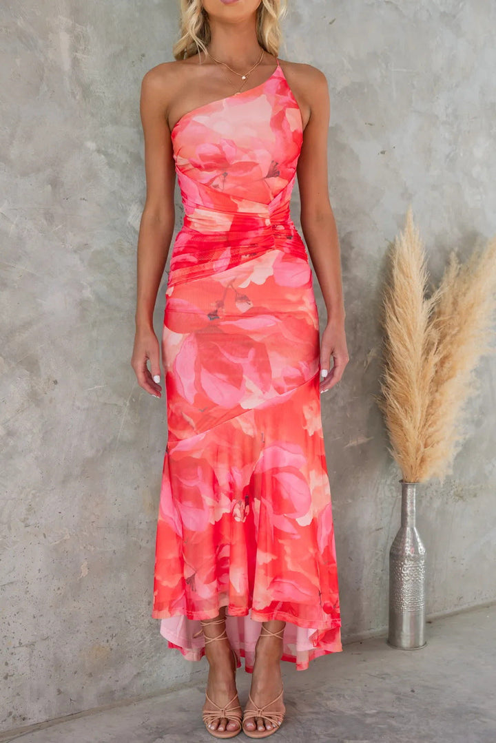 Vibrant floral one-shoulder maxi dress featuring an elegant asymmetric hem, suitable for formal summer occasions.