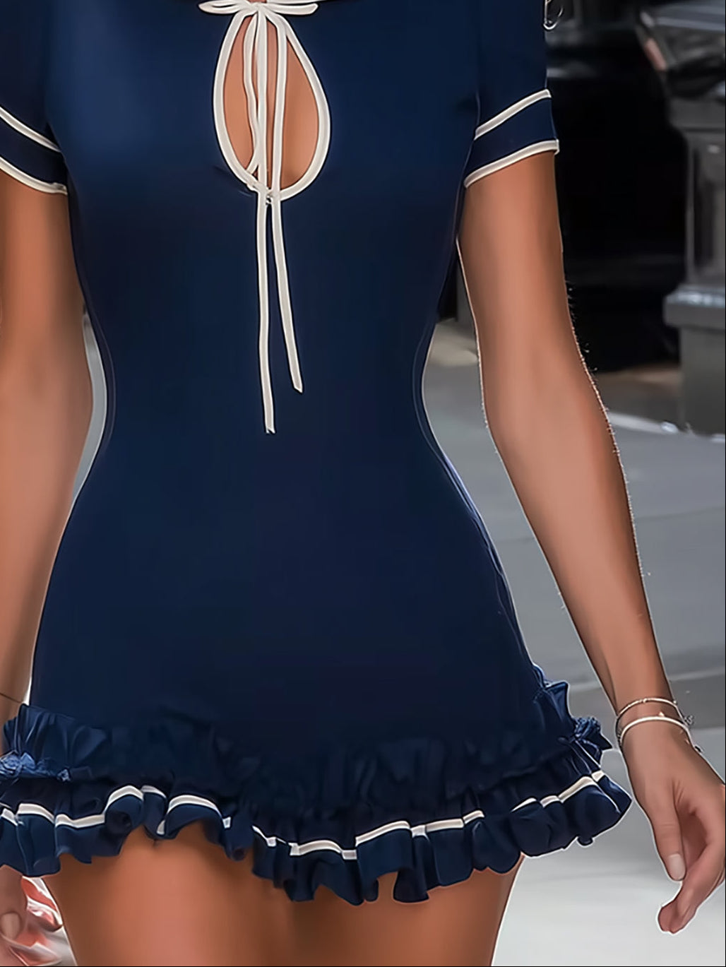 Preppy women's navy mini dress with a sophisticated tie neck, short sleeves, and a feminine ruffled hem detail.