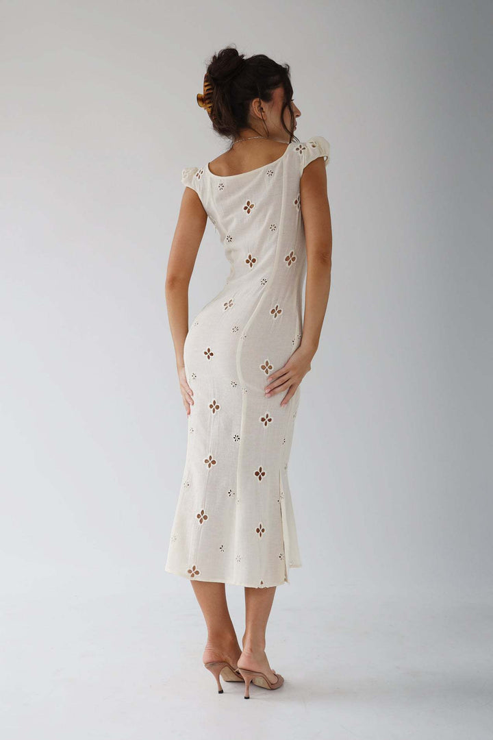 Close-up of the fabric detail on an elegant white midi dress for women's special events.