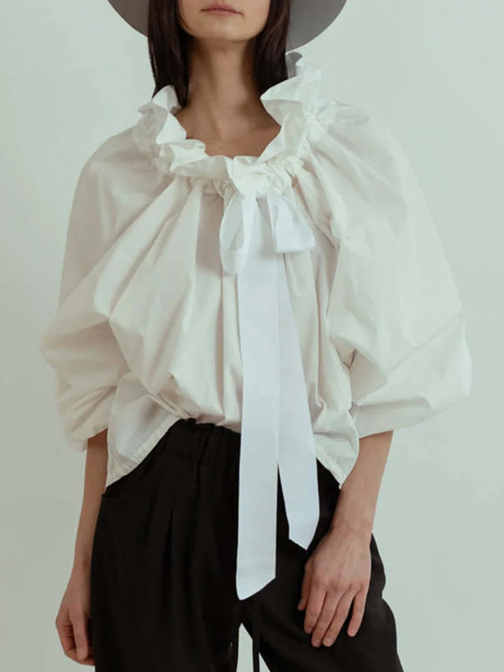 Fashionable women's blouse in white, showcasing prominent puffed lantern sleeves and a delicate bow tie neck.