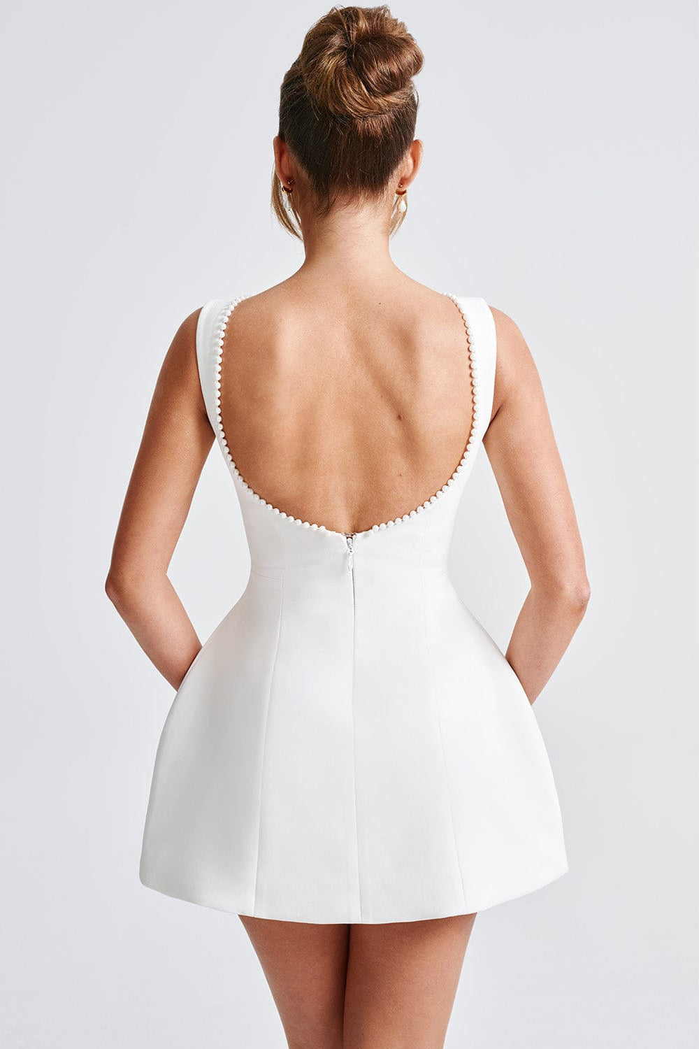 Large statement bow detail on a stylish backless A-line mini dress with pearl trim. Perfect for women's parties.