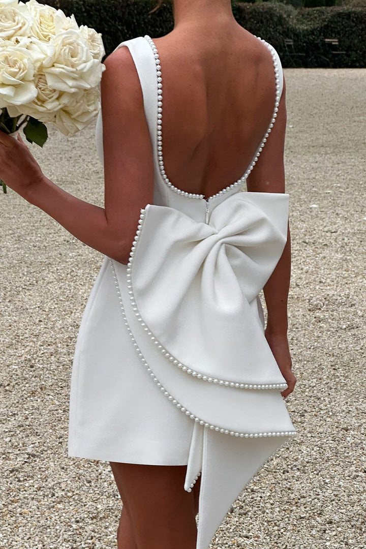 Backless A-line mini dress for women, featuring a stunning statement bow & delicate pearl trim. Ideal party wear.