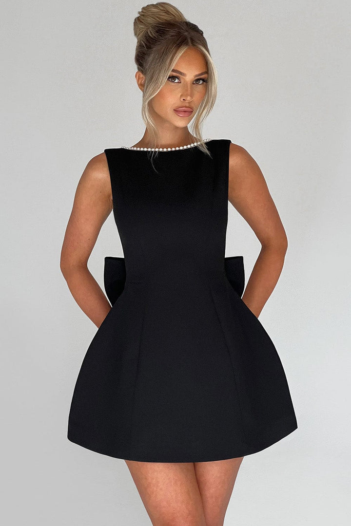 Women's elegant party mini dress, A-line silhouette, showcasing a large statement bow and sophisticated pearl detailing.