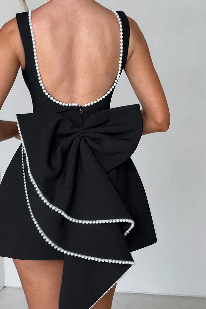 Close-up of delicate pearl trim on an elegant A-line mini dress with a statement bow. Women's fashion essential.