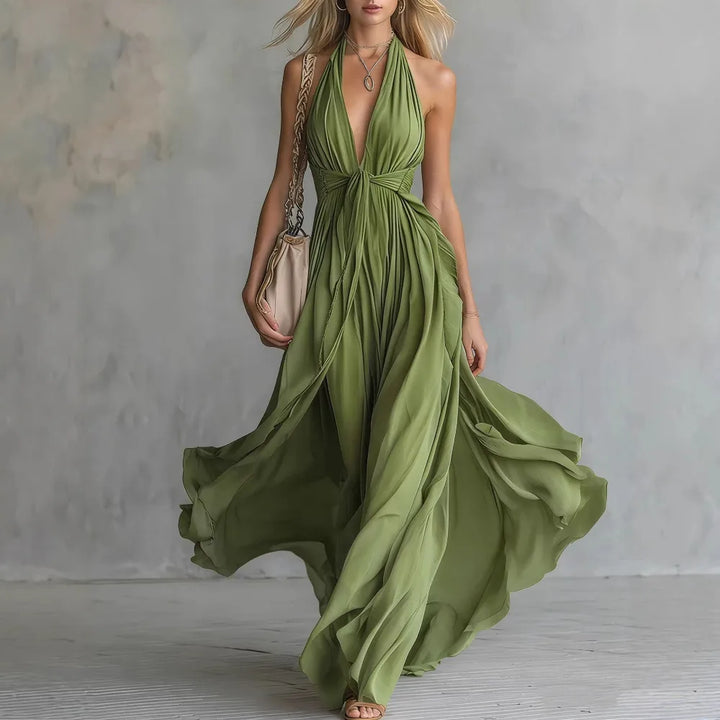 Chic women's backless maxi evening dress with a beautiful pleated flowy skirt and halter neck detail.