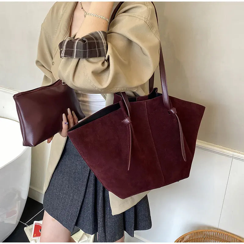 Detail of the handle and stitching on an elegant women's faux suede tote handbag, a durable shoulder bag.