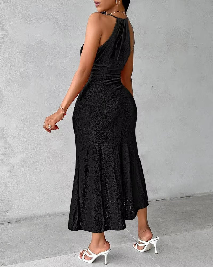 Elegant woman sitting, showcasing the drape of a halter neck maxi dress with a slit for special occasions.
