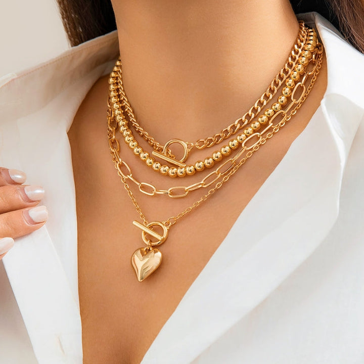 Close-up of a women's layered jewelry piece with small white pearls and shimmering gold-tone pendant and chains.