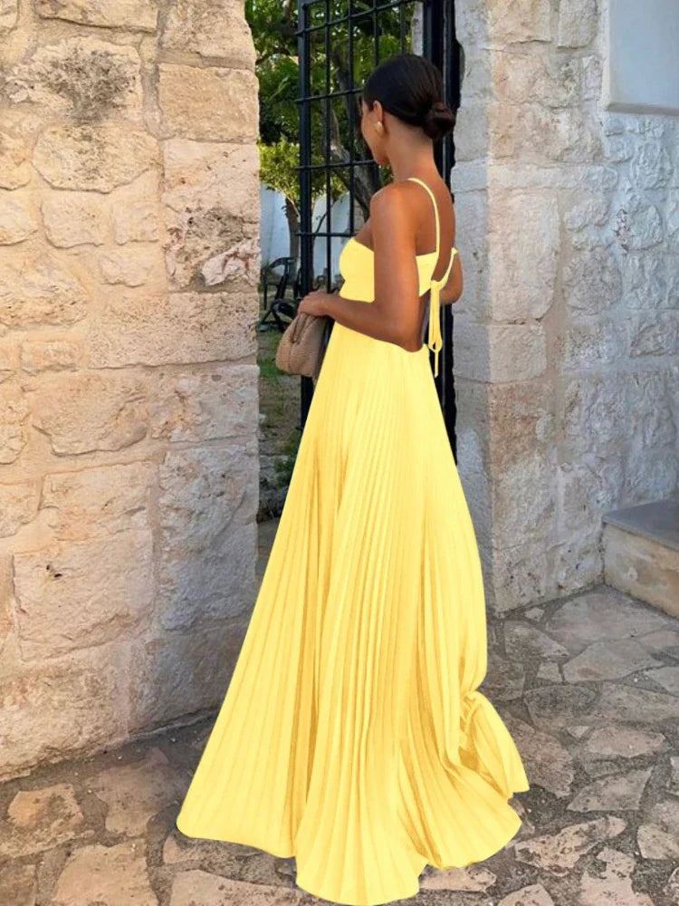 Women's elegant pleated maxi wedding guest dress. Sleeveless, open back, ideal for formal events.