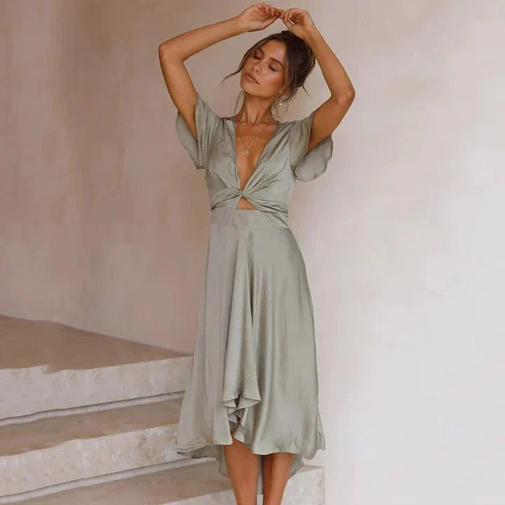 Flowy pink V-neck midi dress featuring tie front, flutter sleeves, and an elegant asymmetric hem.