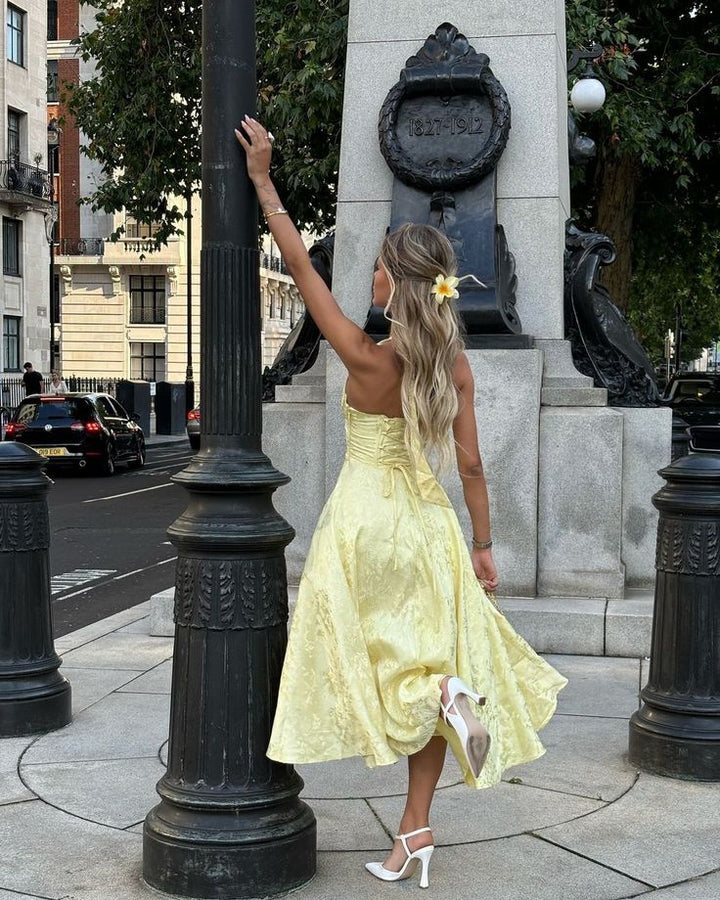 Women's chic yellow midi wedding guest dress featuring a flattering corset and comfortable halter neckline.