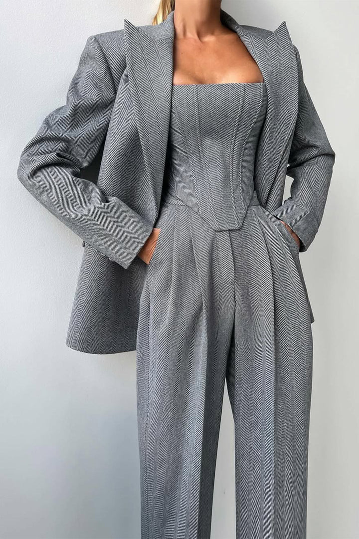 "Elegant women's three-piece suit with structured blazer, bustier top, and wide-leg trousers in classic herringbone weave."