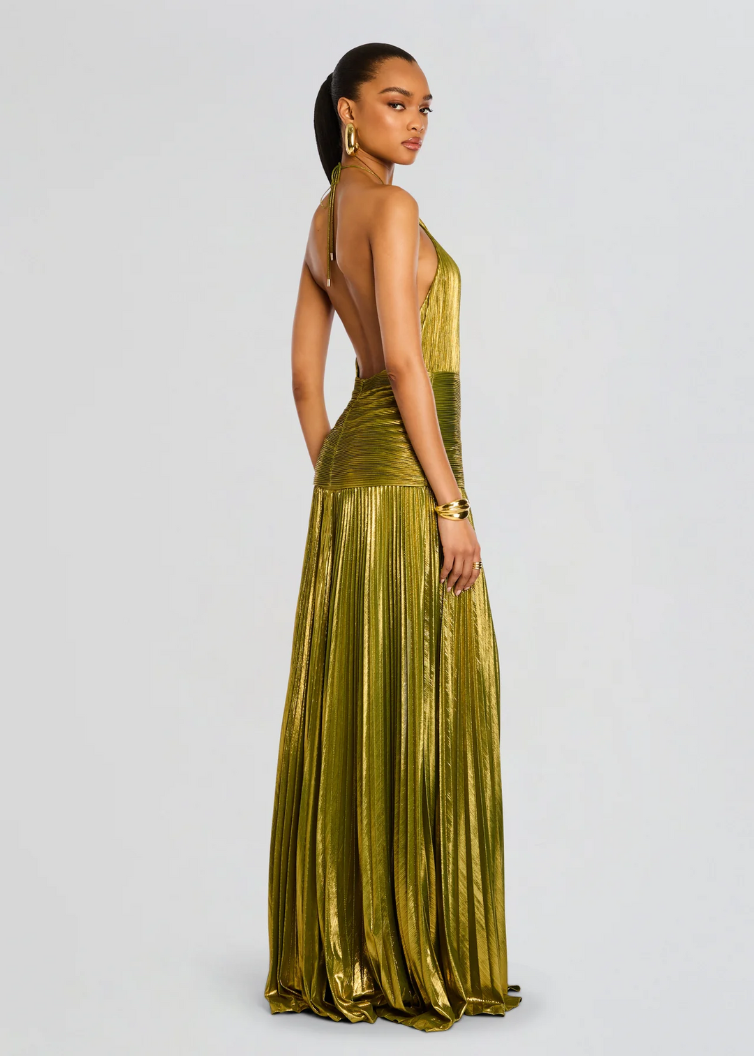 Elegant women's green halter maxi dress with glimmering pleated skirt. A glamorous formal gown for wedding guests or prom.
