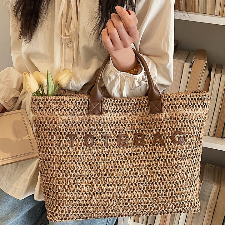 Versatile women's woven shoulder bag, a spacious tote with classic leather handles.