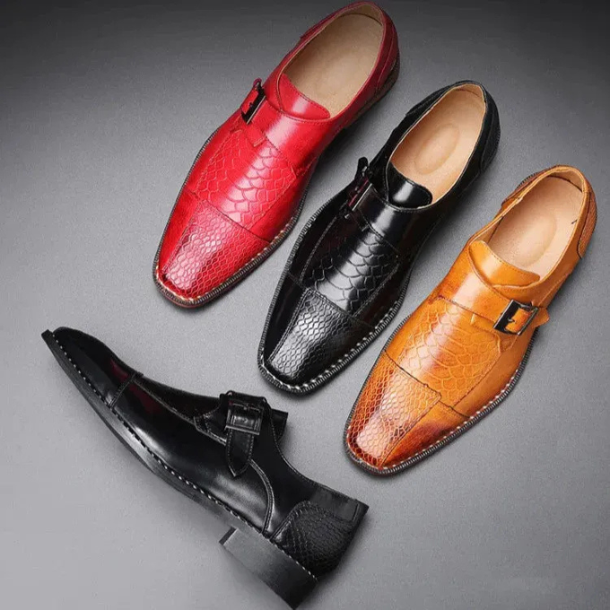Pair of men's striking reptile-textured monk strap dress shoes on a dark background.
