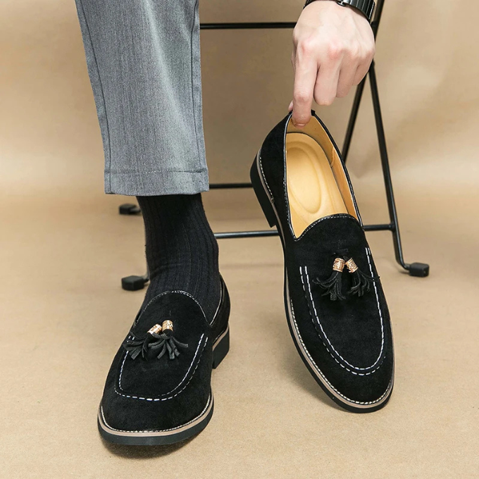 Side profile of a sophisticated men's black velvet loafer with elegant tassels