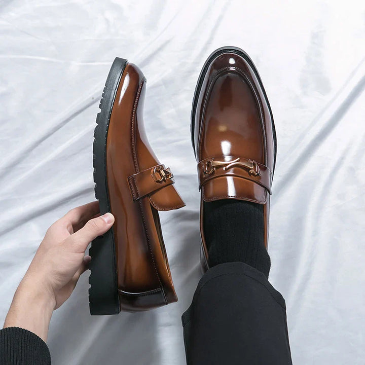 Brown men's slip-on loafers with a sophisticated metal bit detail, perfect for dress or casual outfits.