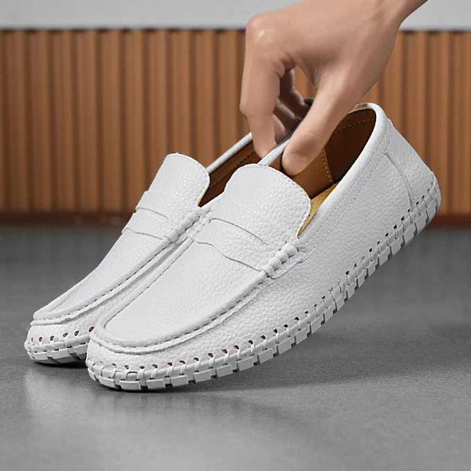 Hand holding a men's full-grain leather loafer, highlighting quality craftsmanship