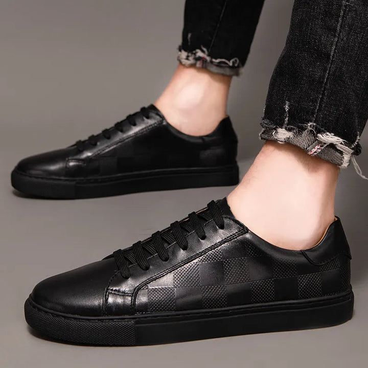 Studio shot of men's elegant black leather low-top sneakers, presenting them as premium casual footwear