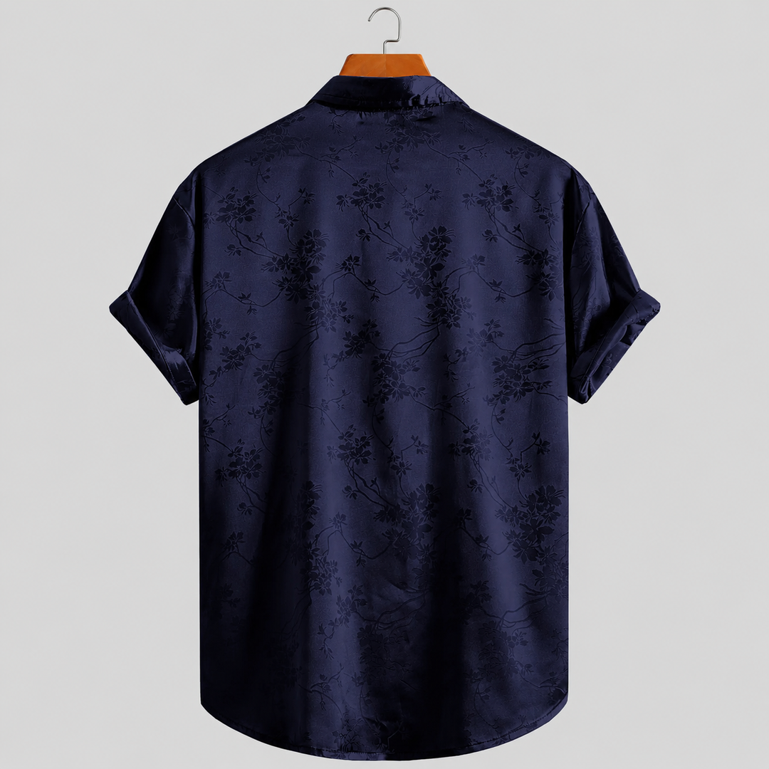 Men's printed satin polo shirt with vibrant floral design. Short sleeves for warm weather casual style.