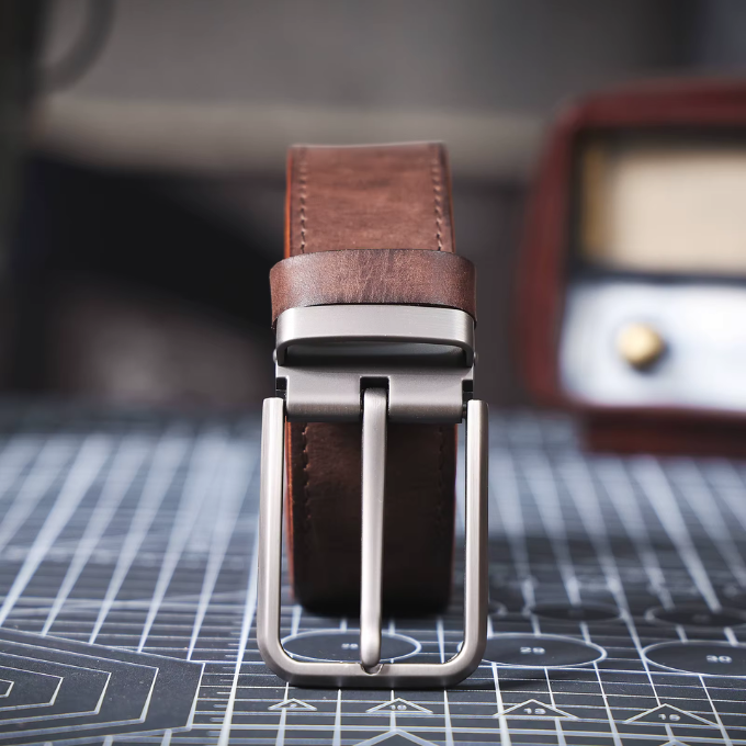 Close-up of the sturdy buckle on a men's full-grain black leather belt, rugged design