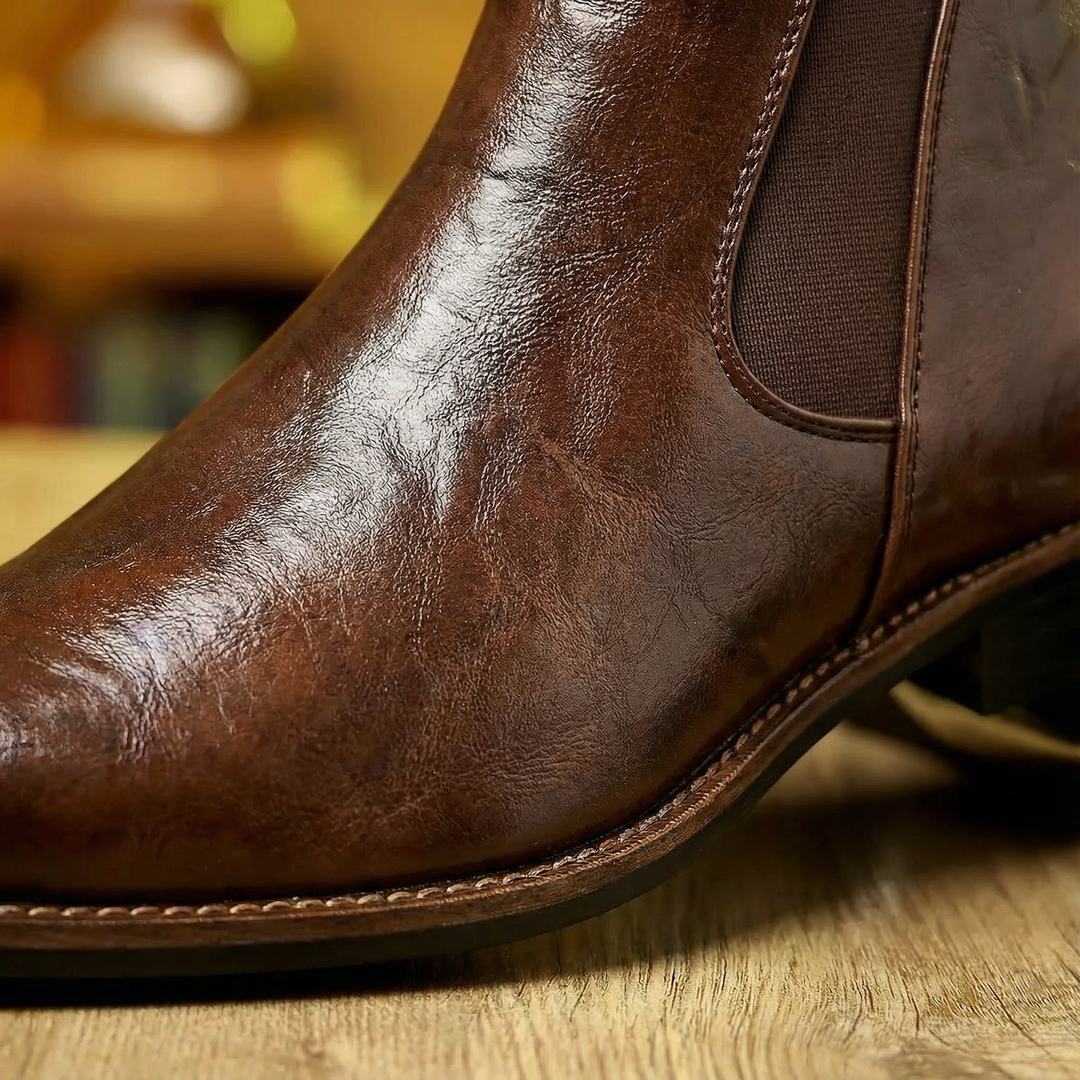 Men's Chelsea boots in tan full-grain leather, against a neutral background, highlighting craftsmanship