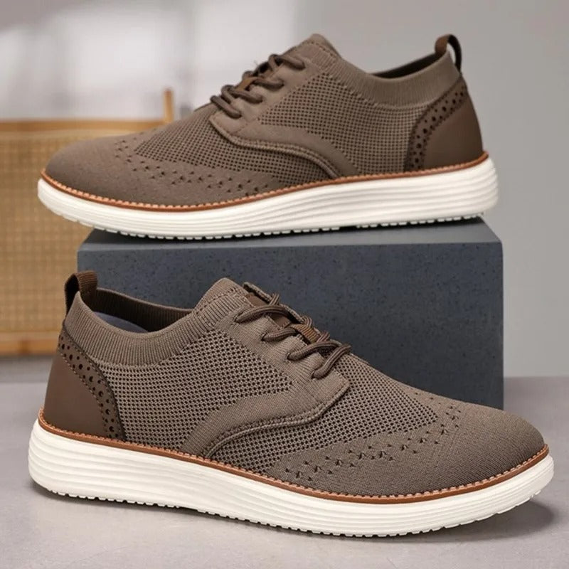 Stylish men's hybrid dress shoes, a blend of formal wingtip and casual sneaker, in a dark color.