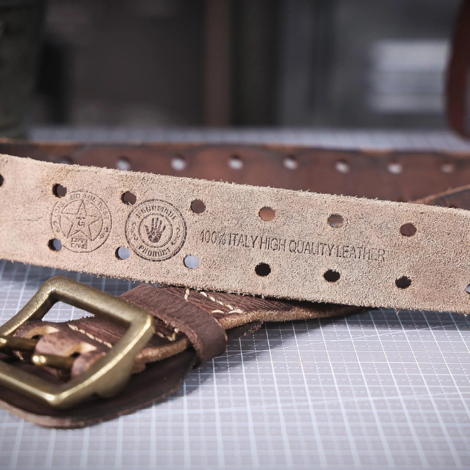 Textured image of a men's distressed Italian leather belt buckle, a key accessory detail.