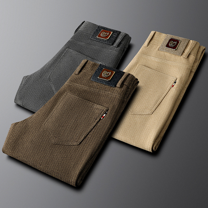 Close-up of khaki herringbone fabric on men's tailored trousers, highlighting the texture and refined detail.