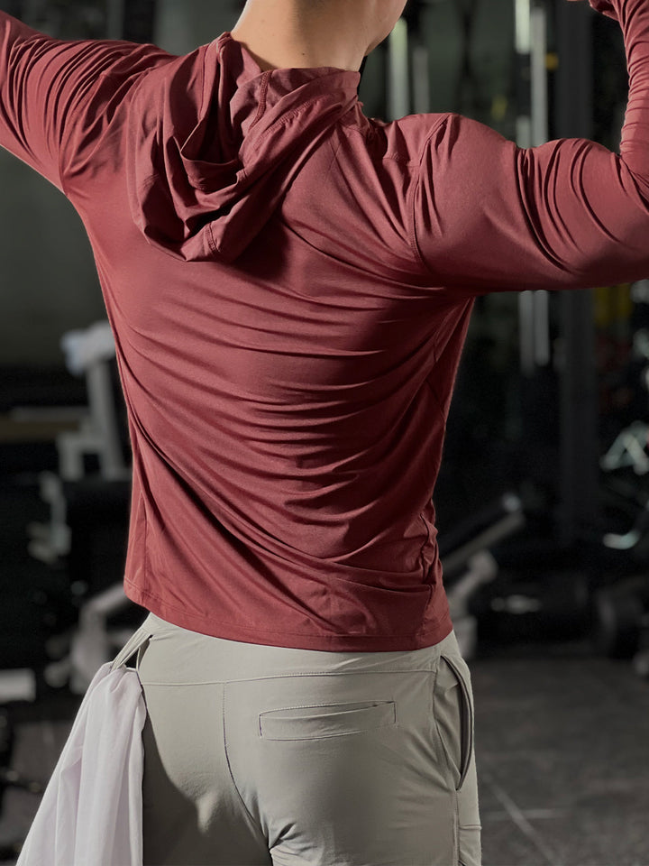 Male athlete warming up in a men's performance baselayer hoodie, demonstrating flexibility