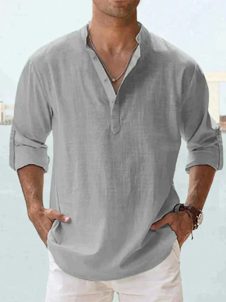 Man wearing a relaxed fit long sleeve button-down men's summer shirt, enjoying a warm weather beach vacation.