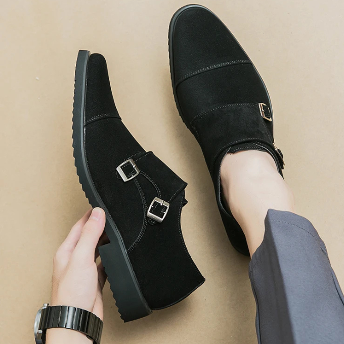 Men's formal footwear: classic black suede double monk strap shoes on a wooden floor.