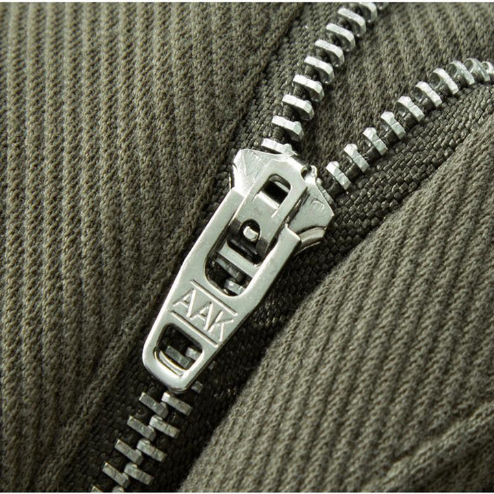 Folded stack of various colored men's tailored stretch denim jeans, including khaki and green.