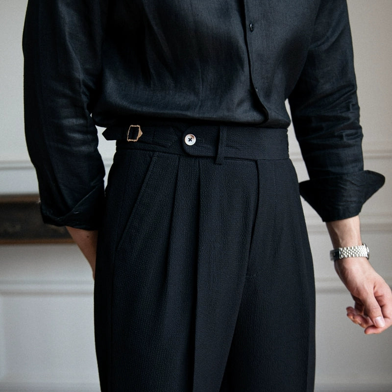 Detail shot of men's tailored high-waist pleated trousers fabric texture & classic pleats.