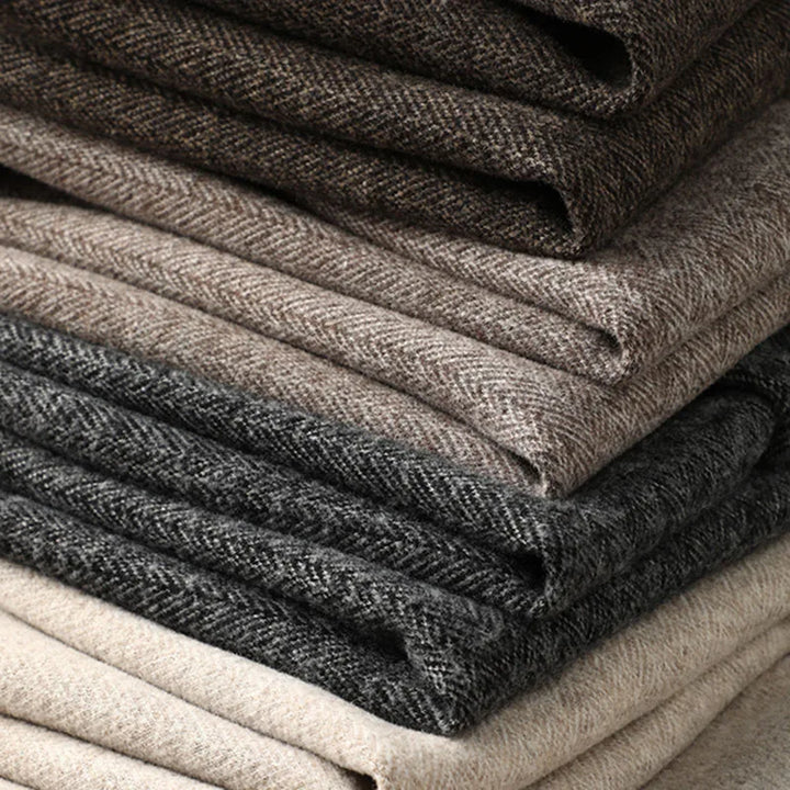 Stack of men's tailored dress trousers in khaki, champagne, brown, and dark grey.