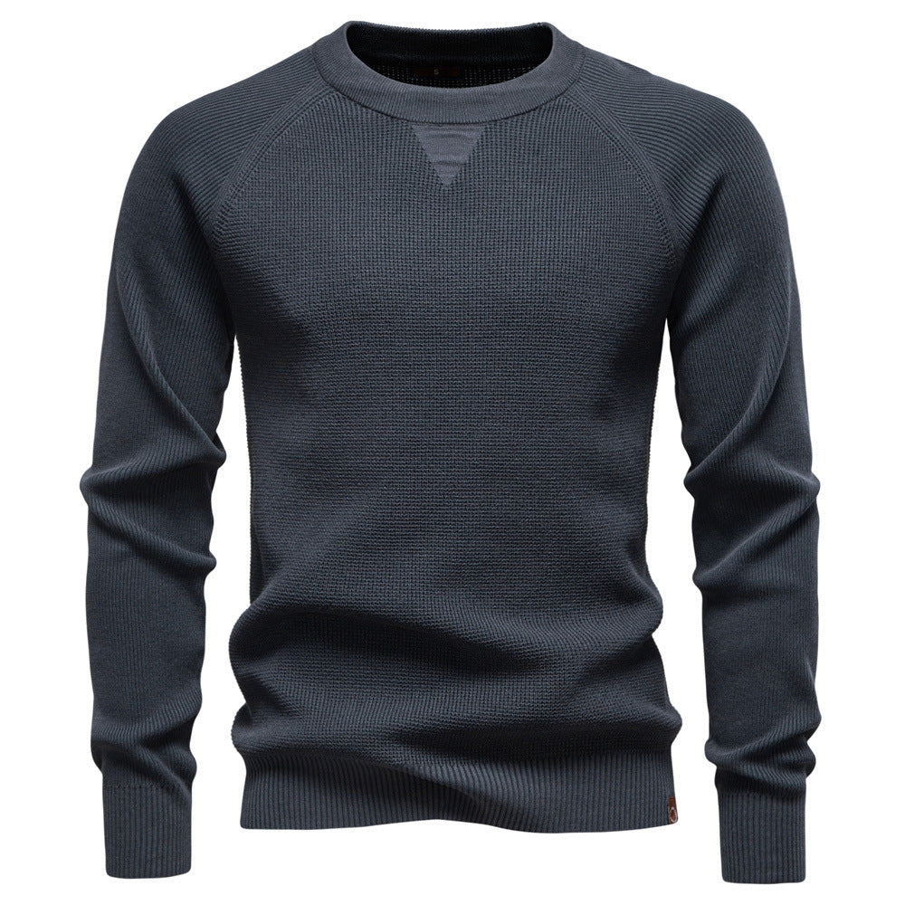 Stack of folded men's waffle knit pullover sweaters in various colors, ready for display.