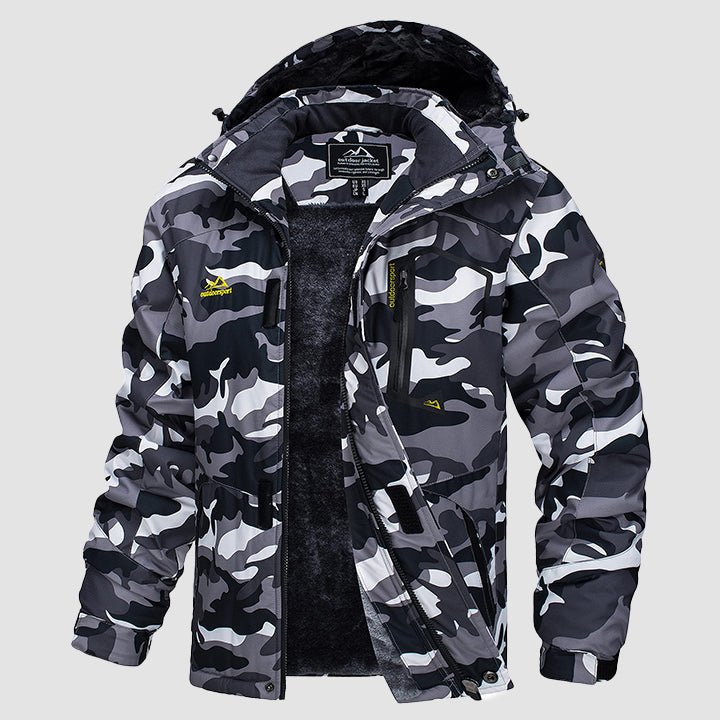 Man in black waterproof ski jacket, hiking uphill in a wintry forest.