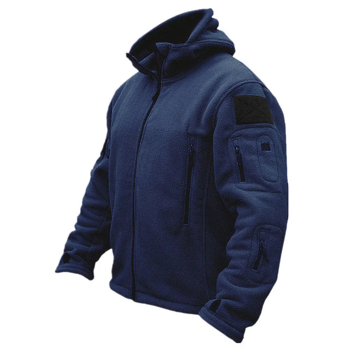 Man hiking in a forest wearing a rugged tactical hooded jacket, perfect functional outerwear for outdoor adventure.