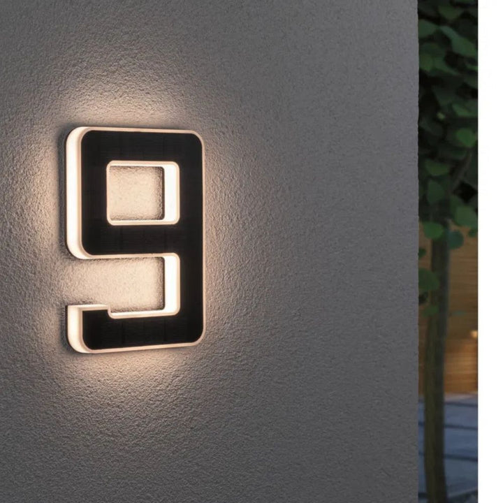 Contemporary black solar address sign with illuminated white numbers, weatherproof outdoor lighting.