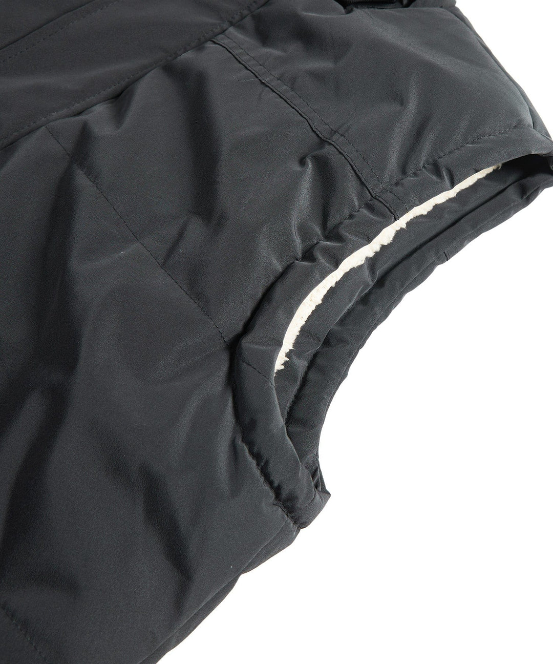 Model zipping up the front of a black insulated puffer vest with a hood
