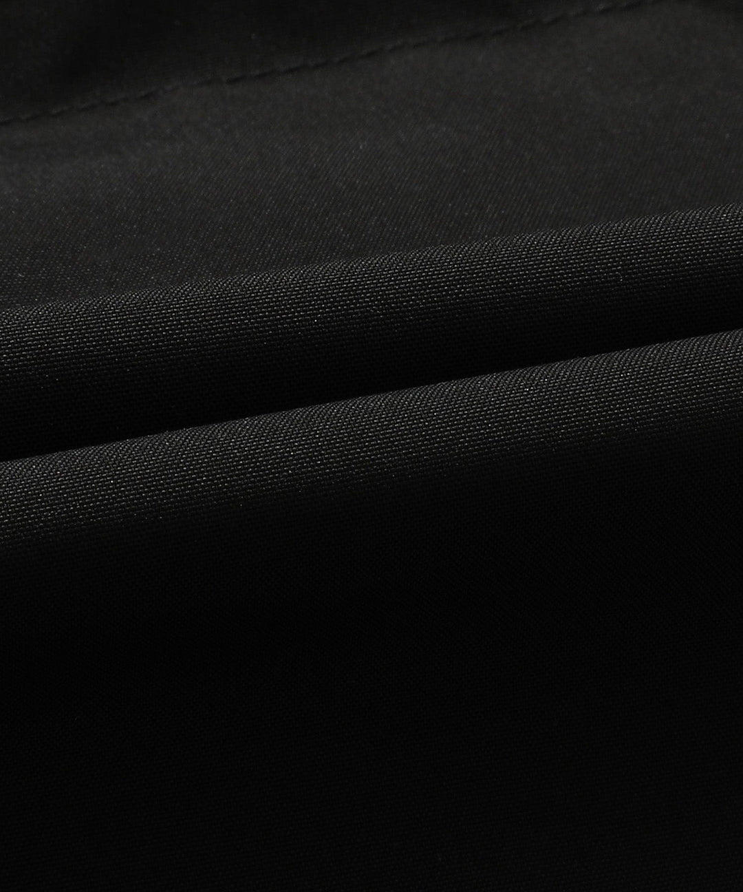 Folded black unisex insulated puffer vest with hood, emphasizing its packability and lightweight design.