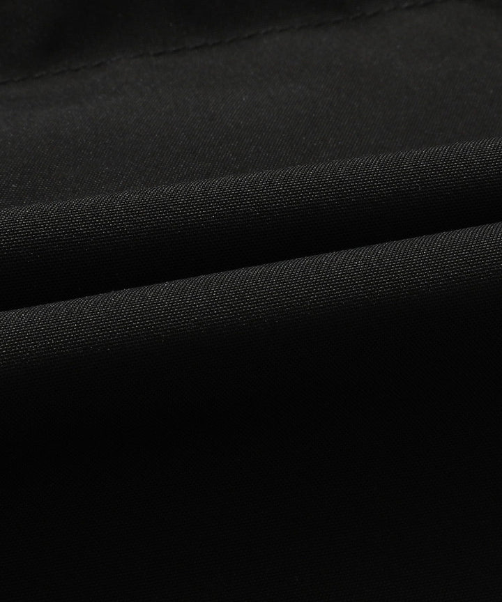 Folded black unisex insulated puffer vest with hood, emphasizing its packability and lightweight design.