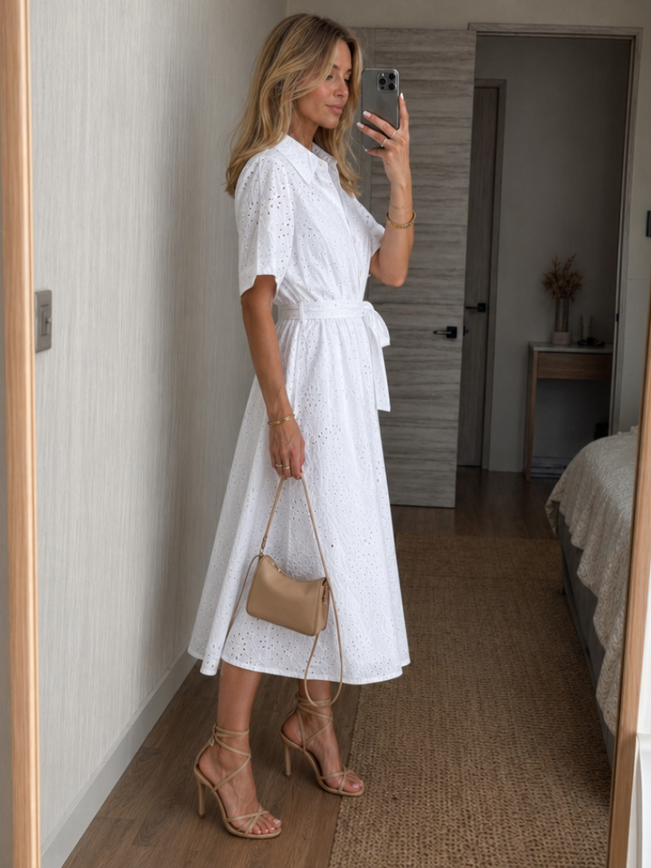Elegant short-sleeve white eyelet midi dress with button-down front & tie waist. Flowy summer daywear.