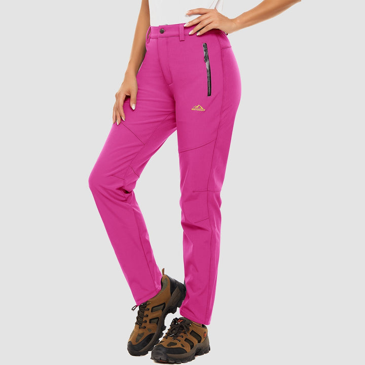 Stack of women's softshell pants in various colors: black, grey, blue, fleece-lined