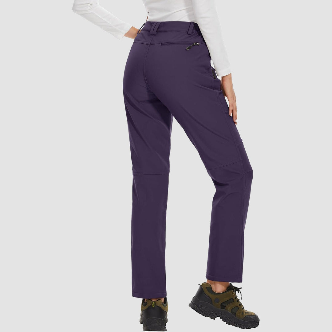 Model showing the stretch of women's black fleece-lined softshell ski pants during a pose